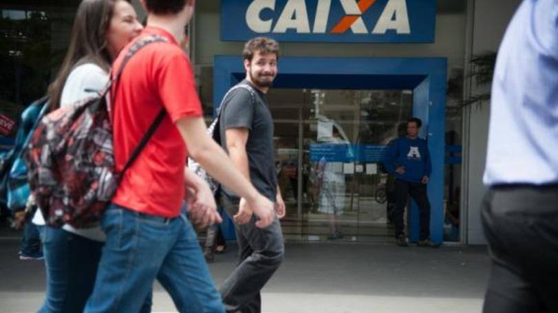 Pessoas em frente a uma agência da Caixa