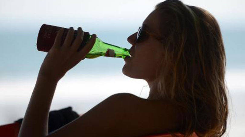 Turista estrangeira bebe cerveja na praia de Kuta na ilha de Bali